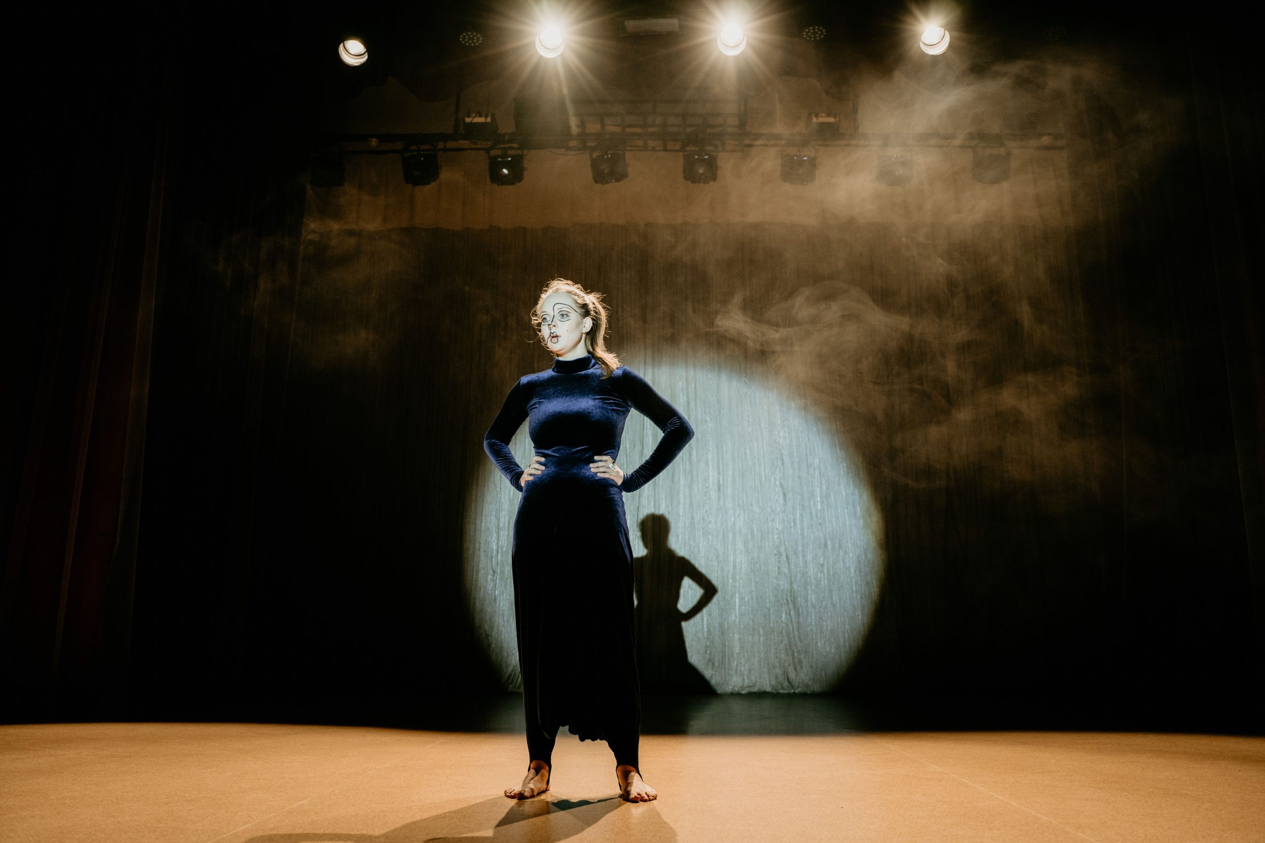 Actor performing confidently under stage lights during a live theatre performance.