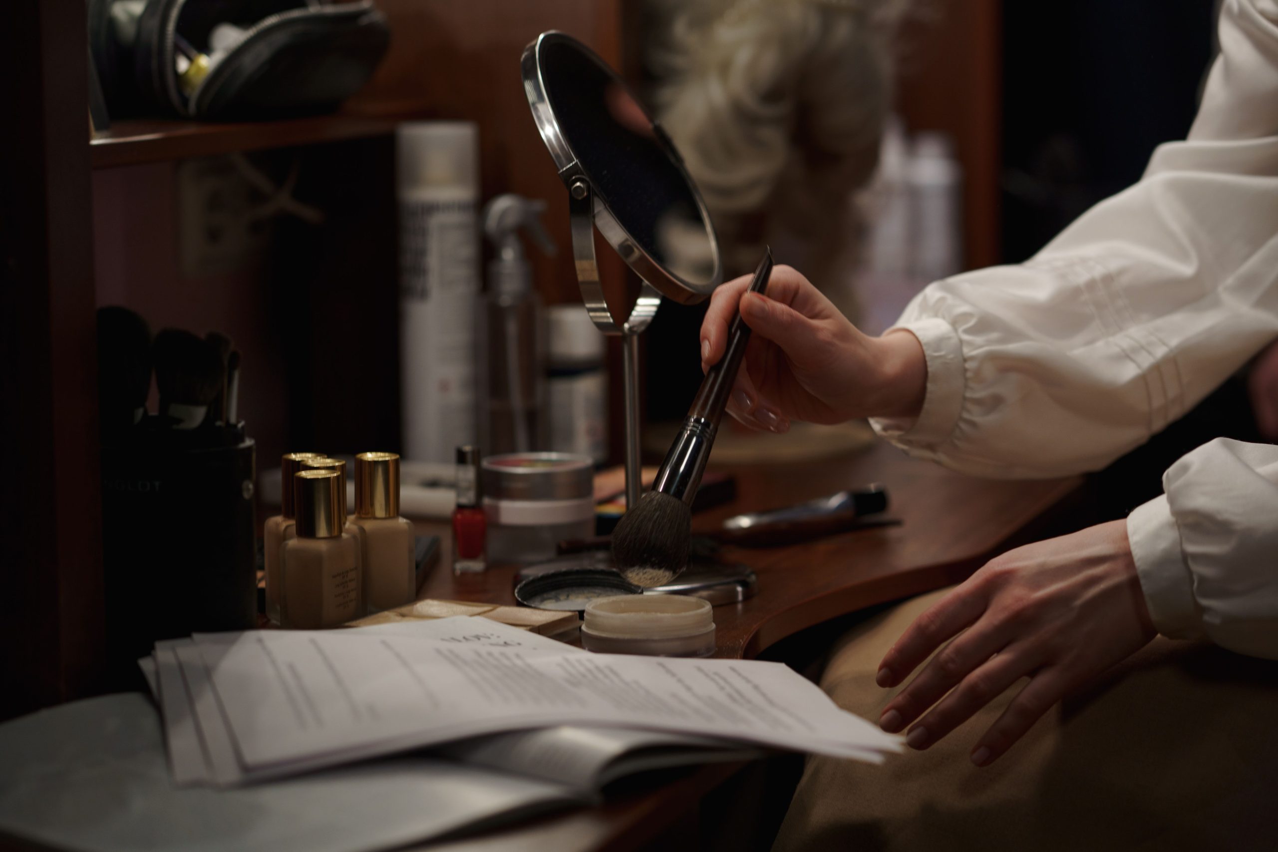 Actress applying makeup backstage while studying their lines before a performance.